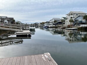 A marina with docked boats, a wooden pier, and residential buildings with balconies. - CANAL HOME - OPEN WEEKS! LINENS PROVIDED! (Ocean Isle Beach)