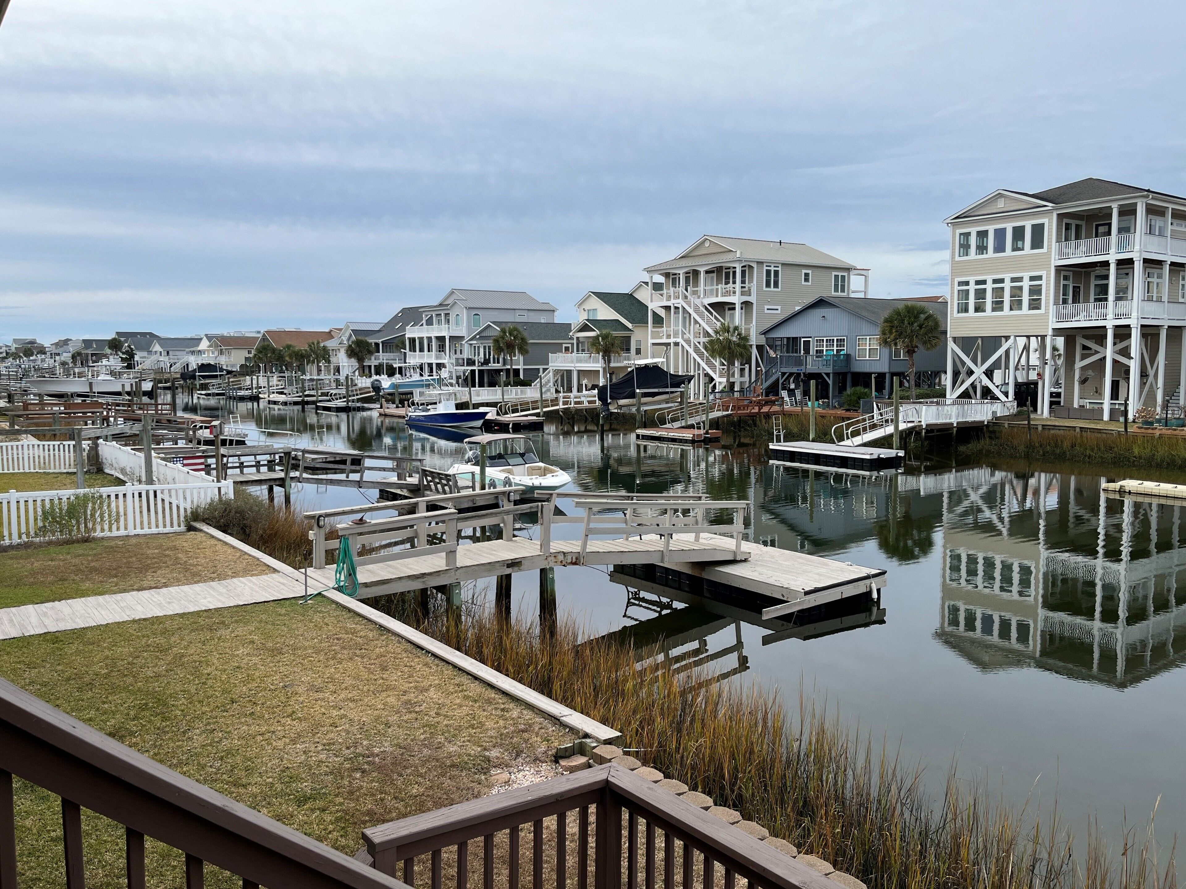 A marina with docked boats, waterfront houses, and a grassy area.