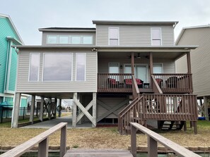 A two-story house with a covered porch and a wooden deck. - CANAL HOME - OPEN WEEKS! LINENS PROVIDED! (Ocean Isle Beach)