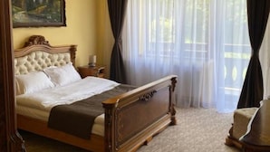 Un dormitorio con una cama grande, un cuadro en la pared y cortinas de encaje.