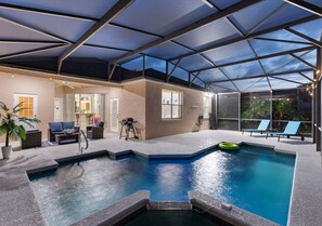 An indoor swimming pool with a glass ceiling, lounge chairs, and a patio area with seating. - 4BR,Heated Pool,Jacuzzi & Dining Oasis near Disney (Haines City)