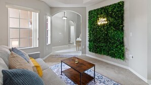Una sala de estar con un sofá, una mesa de centro y una planta verde colgada en la pared.