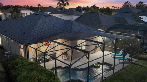 Propiedad residencial con piscina, mobiliario exterior y zona de patio con paredes de vidrio.