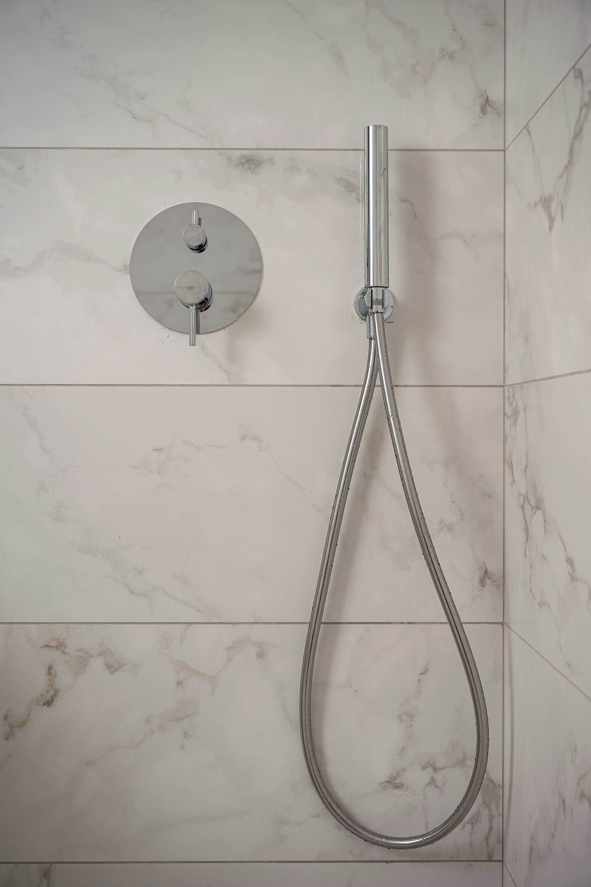Ducha con manguera de mano y panel de control en la pared.
