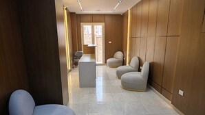 Un pasillo moderno con piso de mármol, paneles de madera y asientos contemporáneos.