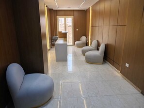 A modern hallway with a marble floor, wooden paneling, and contemporary seating. - Tamaya Hotel Fifth Settlement (Shurtah al-Dakhlah)