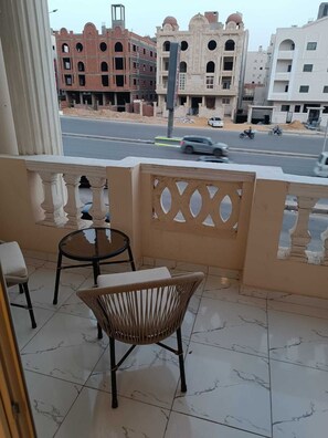 A balcony with a chair and a small table, overlooking a street with buildings in the background. - Tamaya Hotel Fifth Settlement (Shurtah al-Dakhlah)