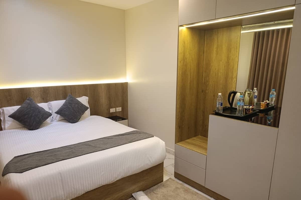 A hotel room with a bed, bedside table, mirror, and a small seating area.