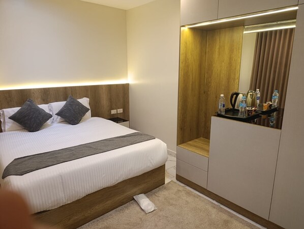 A hotel room with a bed, bedside table, mirror, and a small seating area. - Tamaya Hotel Fifth Settlement (Shurtah al-Dakhlah)