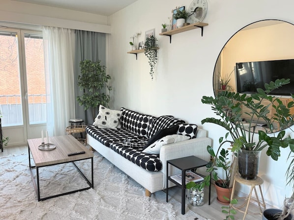 Una sala de estar con sofá, mesa de centro y plantas en macetas.