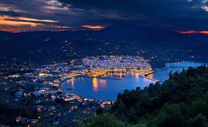 A coastal cityscape at dusk with a prominent bay, illuminated buildings, and surrounding hills. - Stolios Skopelos - Terpsichore Split Level Nest (Skopelos)