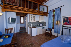 A compact kitchen with a dining area, a TV, and a staircase leading to a loft. - Stolios Skopelos - Terpsichore Split Level Nest (Skopelos)