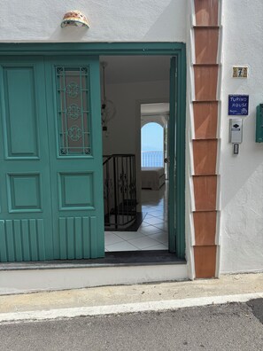 Una porta turchese con una finestra decorativa, una scala che conduce a un balcone, e un cartello che indica che la proprietà è una 'Turino House'.