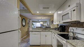 A kitchen with white cabinets, a microwave, a stove, and a dishwasher. - Steps to Beach + Pool | Dog Friendly (Hilton Head Island)