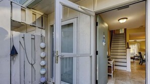 A residential entryway with a sliding glass door, a staircase, and a tiled floor. - Steps to Beach + Pool | Dog Friendly (Hilton Head Island)