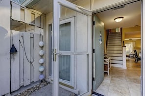 A residential entryway with a sliding glass door, a staircase, and a tiled floor. - Steps to Beach + Pool | Dog Friendly (Hilton Head Island)