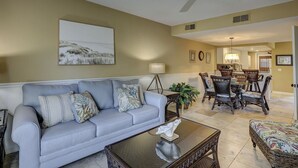 A living room with a sofa, coffee table, and dining area with chairs. - Steps to Beach + Pool | Dog Friendly (Hilton Head Island)