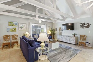 A living room with a sofa, chairs, a TV, artwork, and a ceiling fan. - Palmetto Dunes Villa | Close to Beach & Pool (Hilton Head Island)