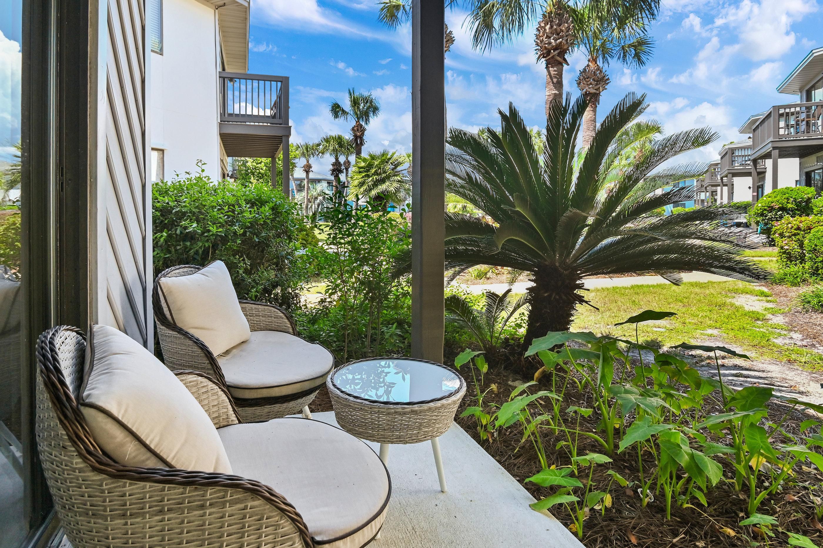 A balcony with wicker furniture, a small table, and a large palm tree.