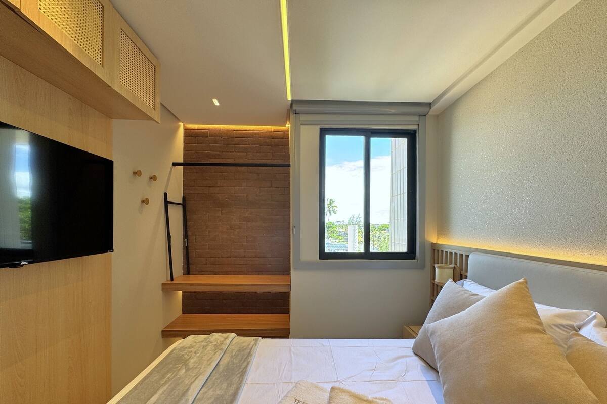 Ein Hotelzimmer mit Bett, Fernseher, Fenster mit Blick und einer Treppe.