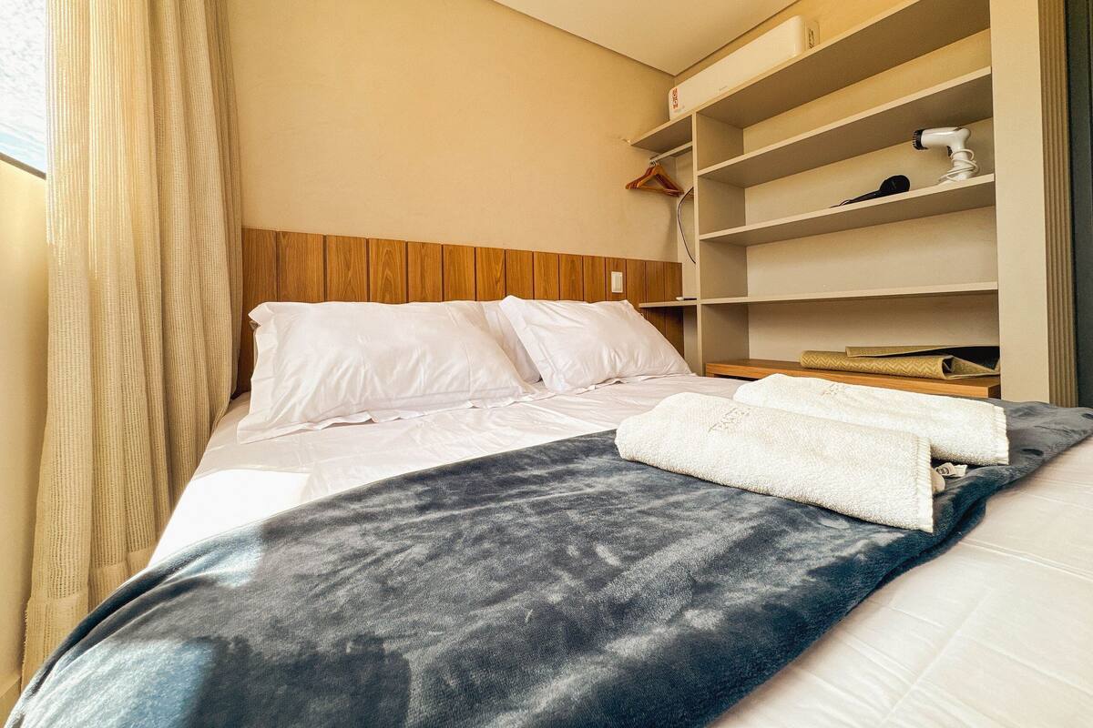 Ein Hotelzimmer mit einem Bett, einem Holzkopfteil, einem Kleiderschrank und einem Fenster mit Vorhängen.