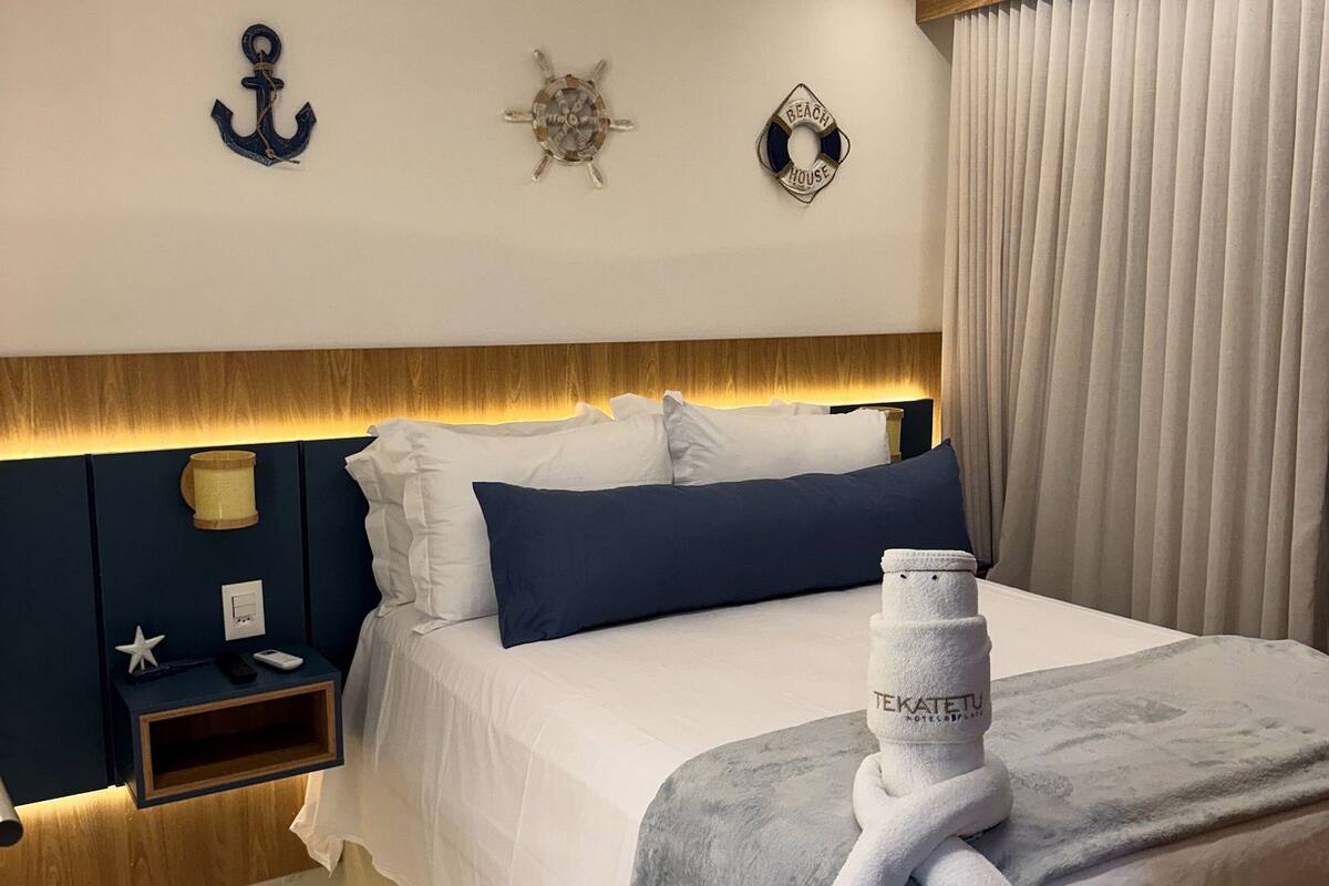 Ein Hotelzimmer mit Bett, Nachttischen, einer Wandlampe und einem Fenster mit Vorhängen.