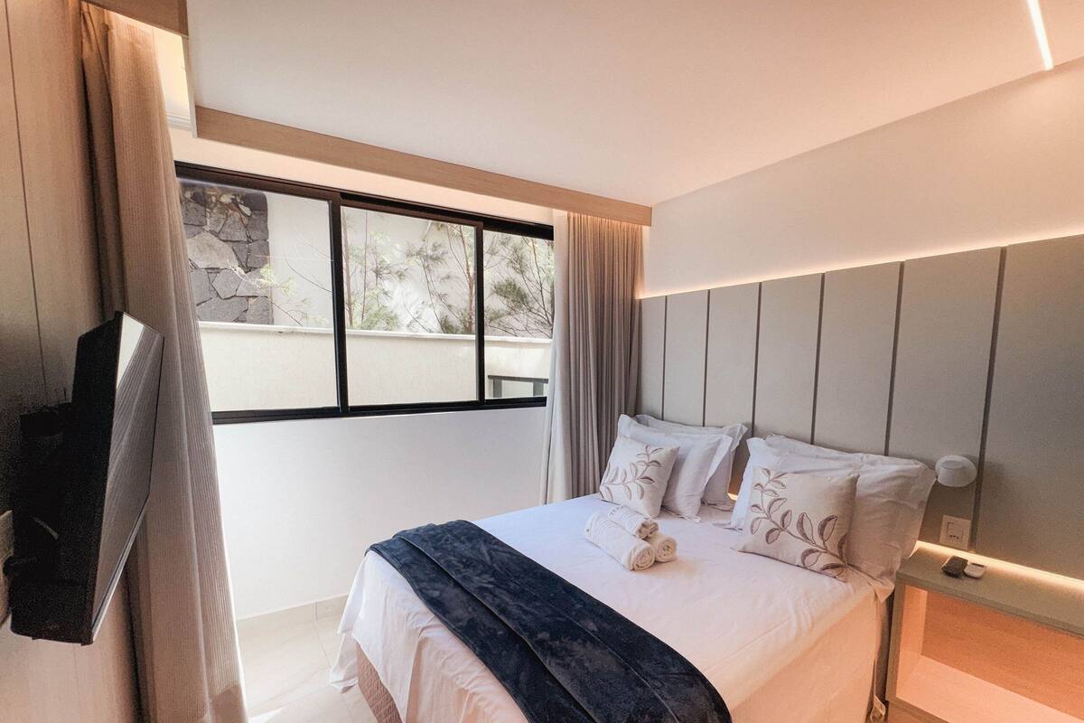 Ein modernes Hotelzimmer mit einem großen Bett, einem Flachbildfernseher und Blick ins Freie.