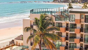 Ein Strandhotel mit Pool, Balkonen und Blick auf Strand und Meer.