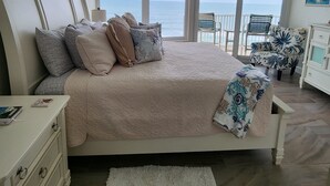 A bedroom with a bed, a ceiling fan, a view of the ocean, a white dresser, and a chair. - OCEANFRONT, beautifully  decorated 2 bedroom condo  Shores Club 602 DBS (Daytona Beach Shores)