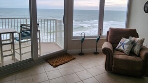 Ein Zimmer mit Blick auf das Meer, ein Sessel, ein kleiner Teppich und eine Stehlampe.