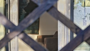 Een kamer met een groot raam, een houten vloer en een bruine bank.