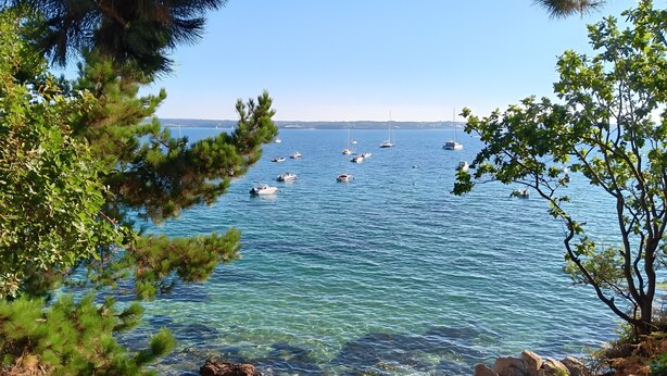 Une vue sur la côte, avec une eau claire, des bateaux et un paysage rocheux.