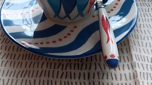 Una taza con diseño de pez y una cuchara sobre un platito.