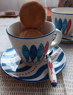 A cup with a fish pattern and a spoon on a saucer. - Le 32 Guest Room – Room 2km from the Beach (Fouesnant)