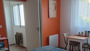 Una habitación con cama, escritorio, silla y ventana con cortinas.