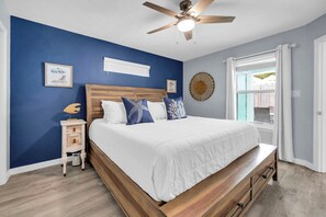 A bedroom with a wooden bed, a nightstand, a ceiling fan, and a window with curtains. - 🏖️Walk to Beach | Golf Cart | Sunnyside Up in PCB🏖️ (Panama City Beach)