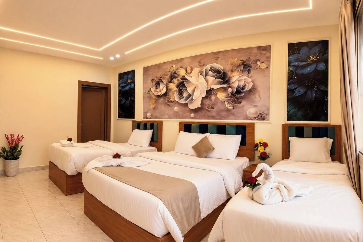 A hotel room with three beds, a large floral mural, and a modern ceiling design.