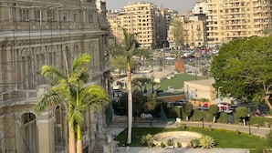 A historic building with classical architecture, a flag, and a well-maintained courtyard with palm trees. - Garden City Tahrir Downtown (Cairo)