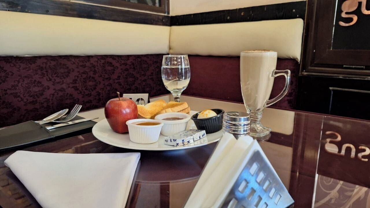 A dining table with a plate of food, a glass of water, a glass of milk, and a small bowl of soup.