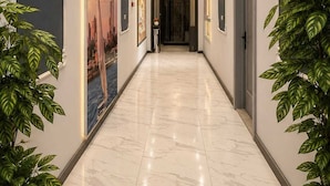 A hallway with marble flooring, wall-mounted lights, framed artwork, and potted plants. - Garden City Tahrir Downtown (Cairo)