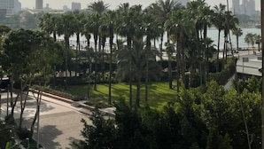 A view of a cityscape with a prominent tower, palm trees, and a body of water. - Garden City Tahrir Downtown (Cairo)