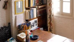 A room with a wooden desk, bookshelves, and a window with curtains. - Villa Pinelopi (Mykonos)