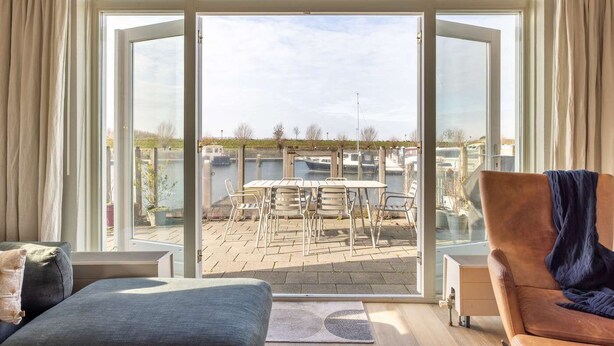Una habitación con un amplio ventanal corredera que da a un patio exterior con una mesa y sillas.