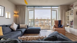 Un salón moderno con sofá, sillón y un ventanal con vistas a un patio.