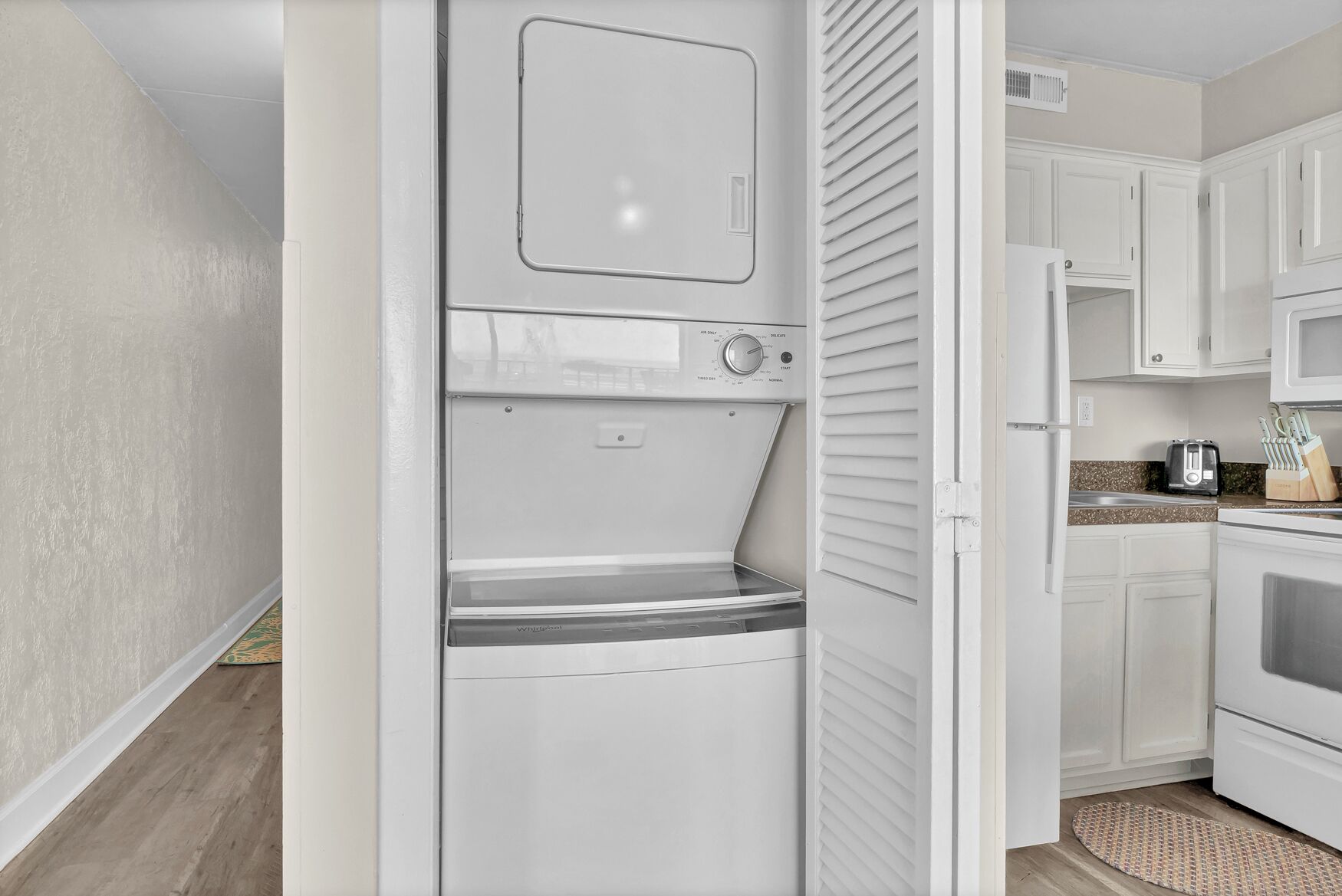 A compact kitchen with a built-in washer and dryer, a toaster, and a knife block on the counter.