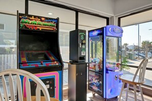 A room with arcade games, a vending machine, and a window with a view of the street. - Beachfront Pet-Friendly 2BR Condo Walkable to Boardwalk (Carolina Beach)