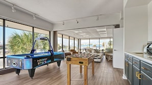 Um quarto espaçoso com mesa de pebolim, mesa de bilhar e cozinha.