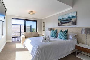 Une chambre d’hôtel avec un grand lit, un canapé, un tableau et une vue sur l’extérieur.