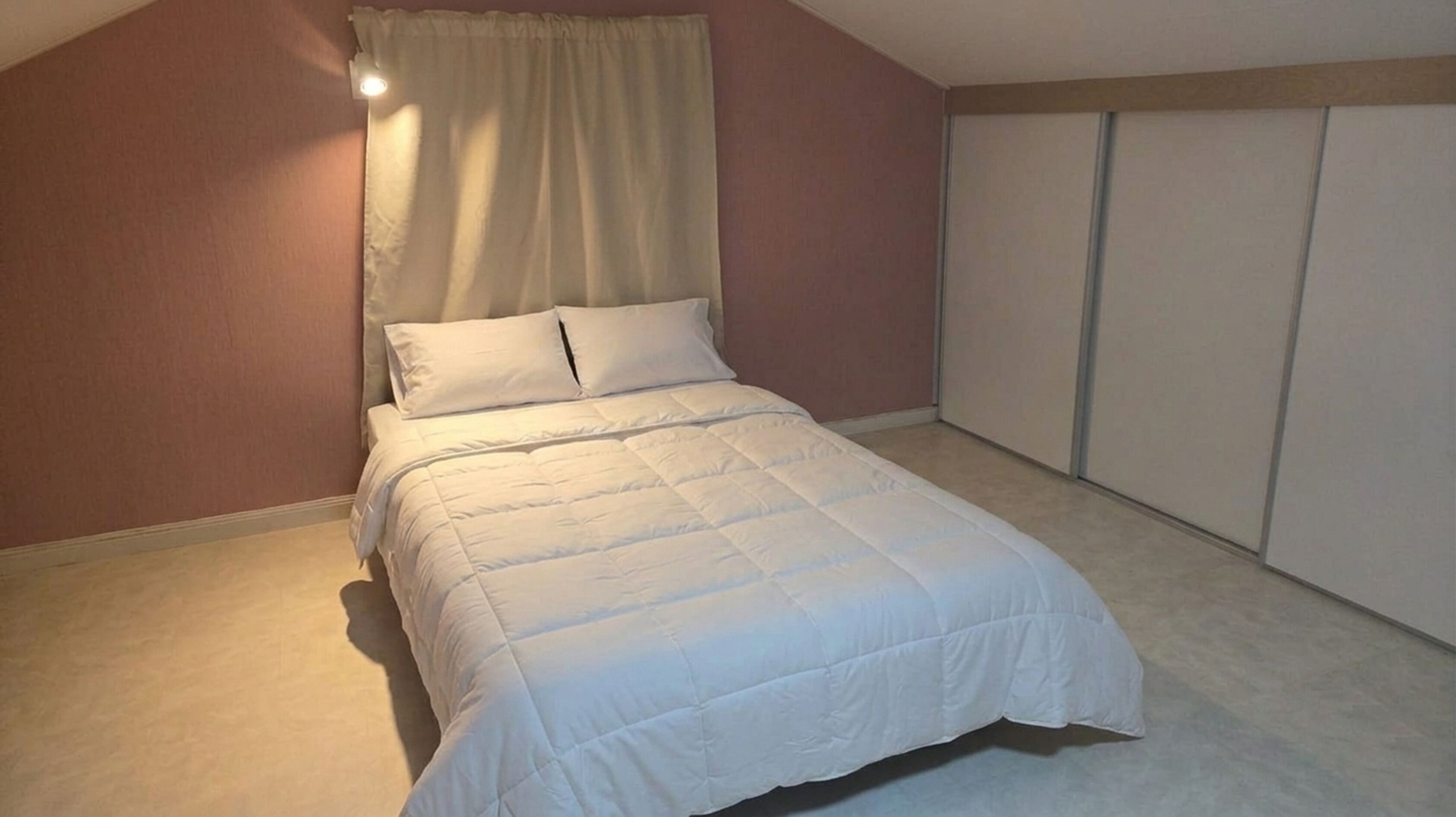 Une chambre à coucher avec un lit, une fenêtre avec des rideaux, une armoire et un luminaire.