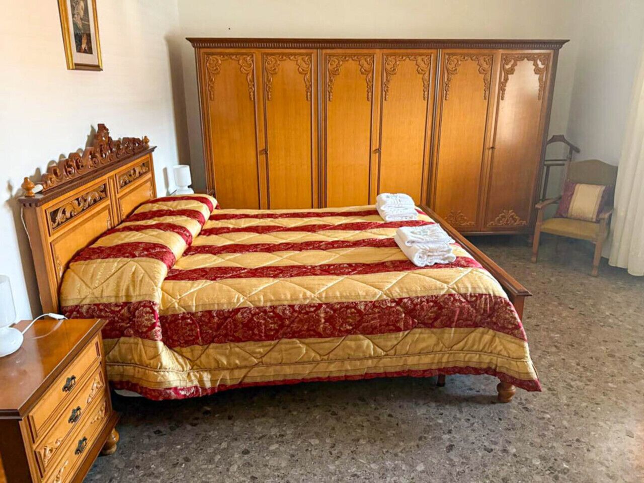 Ein Schlafzimmer mit einem großen Bett, einem Holzschrank, einem Schminktisch und einem Stuhl.